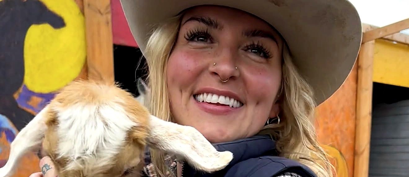Une cavalière tenant un chevreau dans ses bras