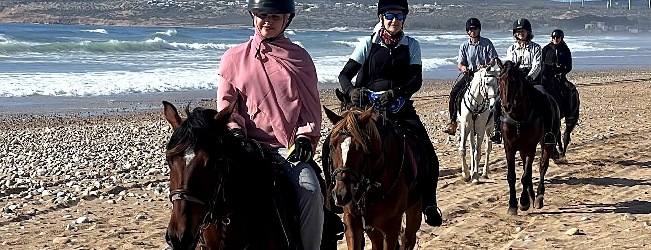 Un groupe de cavaliers en file sur la plage
